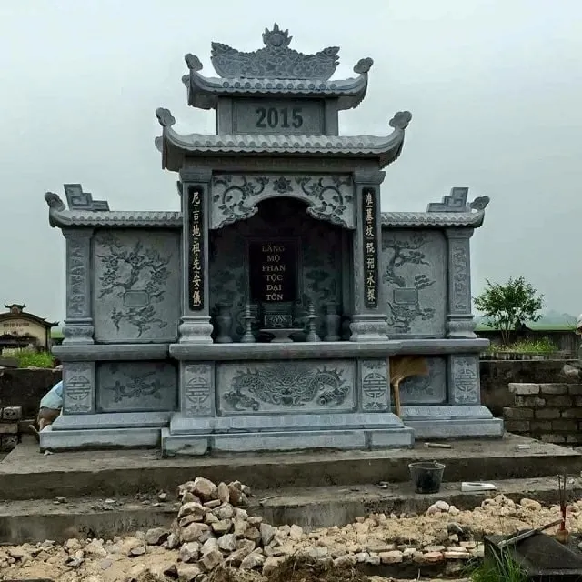 Mẫu lăng thờ đá cánh liền khối 2 mái đao với các hình mây đơn giản trên đỉnh đao, đỉnh lăng khắc họa lưỡng long chầu nguyệt